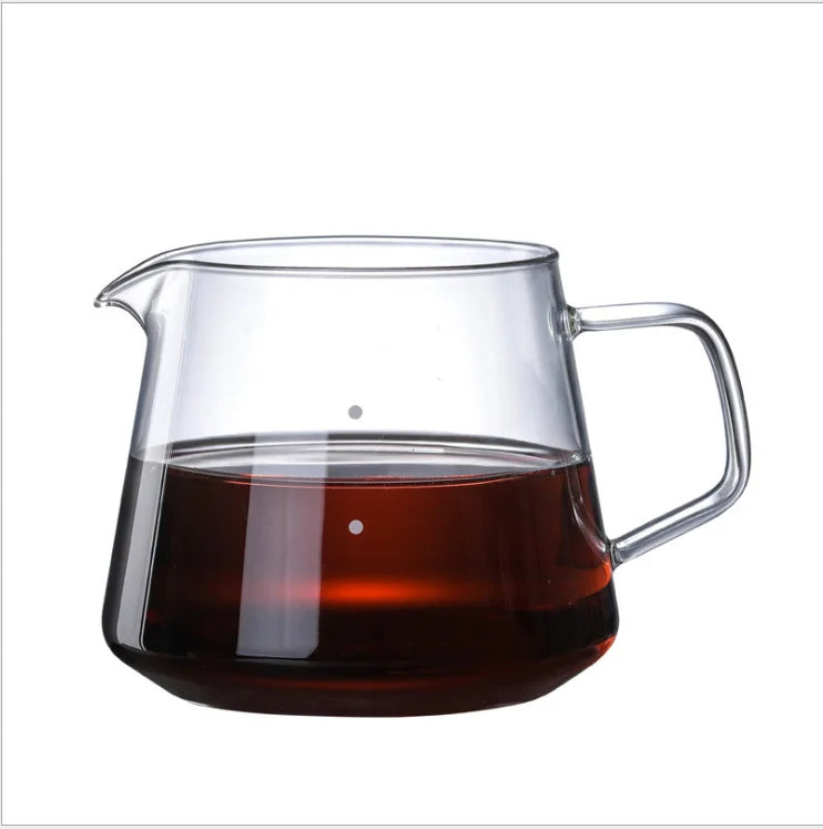 Clear glass teapot with a handle filled with dark liquid on a white background