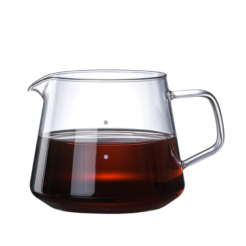 Clear glass teapot with a handle filled with dark liquid on a white background